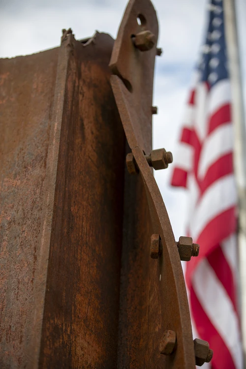 Photo of piece of Twin Tower with flag in background.